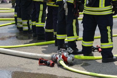 Blick auf Feuerwehrpersonal, welches zwischen Wasserschläuchen steht. Symbolfoto von Pixabay